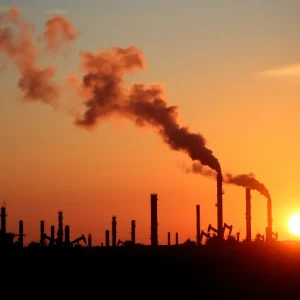 Silhouette of oil refineries against a sunset sky